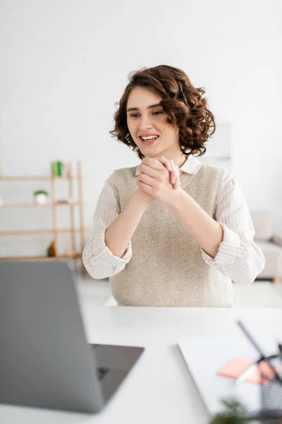 ノートパソコンでオンラインレッスン中に手話を教えている間に手を握りしめている陽気な女性 — ストック写真