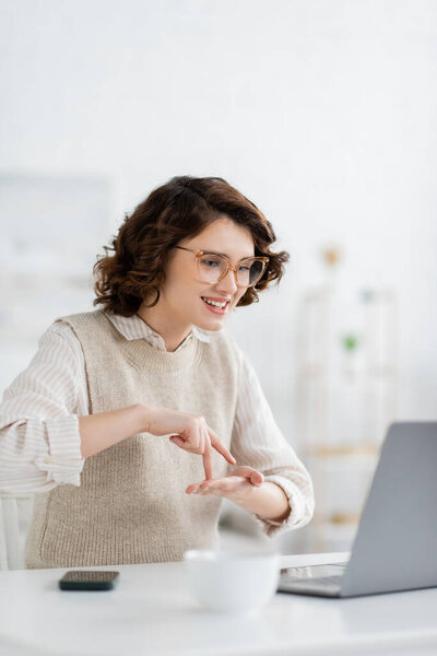 счастливая женщина, демонстрирующая стендап во время обучения языку жестов во время онлайн урока на ноутбуке 