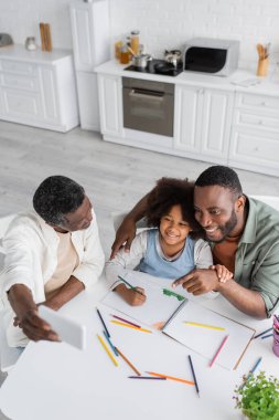 overhead view of middle aged african american man taking selfie on smartphone with son and granddaughter  clipart