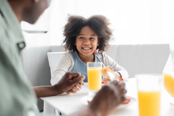 stock image cheerful african american girl looking at grandfather during breakfast at home 