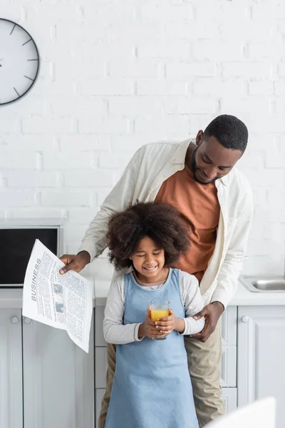 Happy African American Man Holding Newspaper Looking Cheerful Daughter Glass — Stock Photo, Image