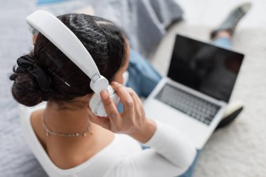 Podcast dinlerken ve laptop kullanırken kablosuz kulaklık takan Afrikalı Amerikalı öğrencilerin en iyi görüntüsü 