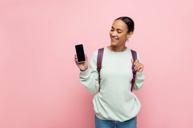 Neşeli Afrikalı Amerikalı öğrenci pembe ekranda boş ekranla cep telefonuna bakıyor. 
