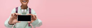 Beyaz ekranda pembe pankartta izole edilmiş akıllı telefonlu neşeli Afrikalı Amerikalı kadın görüntüsü. 