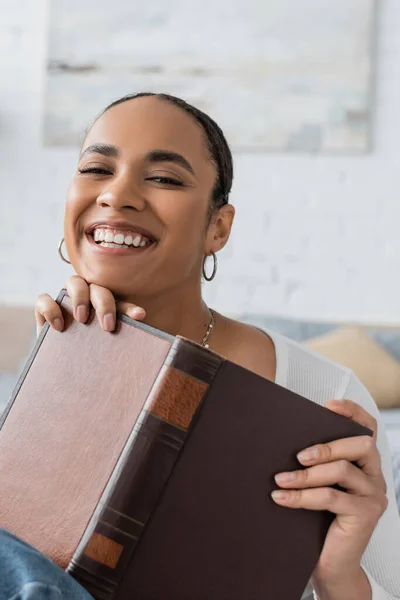 Overjoyed African American Student Holding Book While Studying Home — Stock Photo, Image