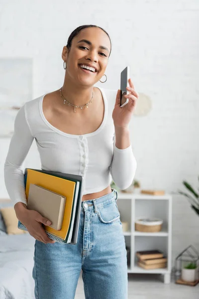 Carefree African American Student Holding Cellphone Notebooks Bedroom — Stock Photo, Image