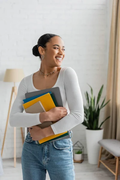 stock image Cheerful african american student holding notebooks at home 