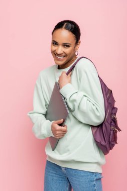 Sırt çantalı ve dizüstü bilgisayarı pembe olan Afro-Amerikan öğrenci. 