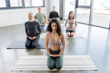 Yoga stüdyosunda Thunderbolt Asana 'da çok ırklı insanlar kapalı gözlerle meditasyon yapıyor. 