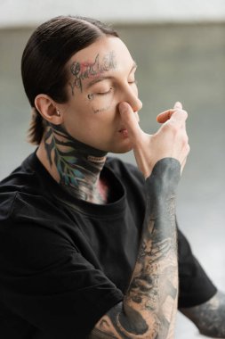 Tattooed man practicing nostril breathing and meditation in yoga class  clipart