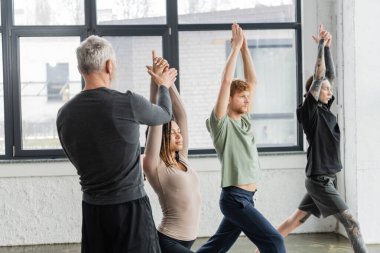 Olgun koç, yoga stüdyosunda Crescent Lunge Asana 'yı yapan Afrikalı Amerikalı kadına yardım ediyor. 