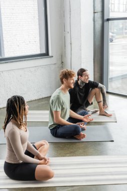 Yoga dersinde paspaslar üzerinde konuşan çok ırklı genç insanlar. 
