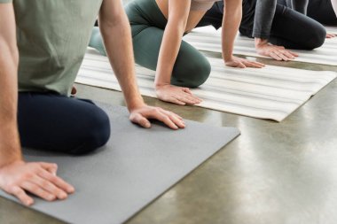 Yoga dersinde minderlerin üzerinde Half Pigeon Asana yapan insanların görüntüsü. 