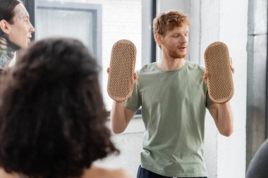 Genç kızıl saçlı adam Sadhu tahtasına bakıyor ve yoga sınıfındaki insanlarla konuşuyor. 