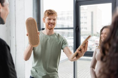 Yoga stüdyosunda sadhu tahtasını bulanık etnik grupların yakınında tutan olumlu bir adam. 