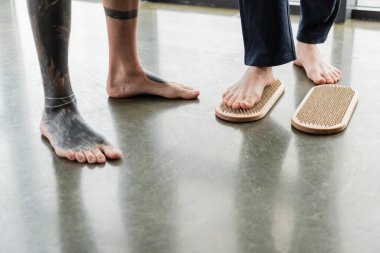 Yoga dersinde dövmeli koçun yanında duran adamın sadhu tahtasında duruşu. 