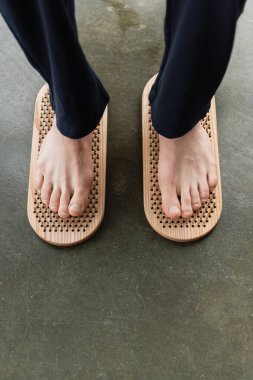 top view of cropped man standing on nails during yoga practice in yoga studio clipart