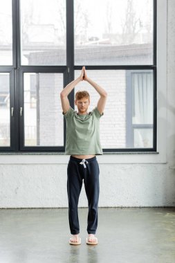 Kızıl saçlı adam, yoga stüdyosunda elleri havada bir şekilde Sadhu tahtasında duruyor. 