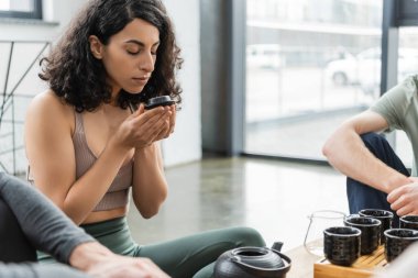 Orta Doğulu kadın elinde çaydanlık kapağı tutuyordu ve yoga stüdyosunda erkeklerin yanında puer kokuyordu. 