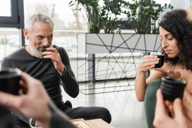 Mutlu olgun bir adam yoga stüdyosundaki orta doğulu kadına bakarken Puer çayı içiyor. 