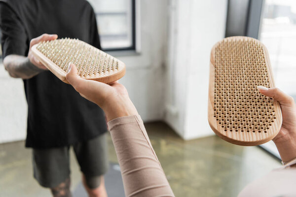 Cropped view of african american woman giving sadhu board to tattooed man in yoga studio 