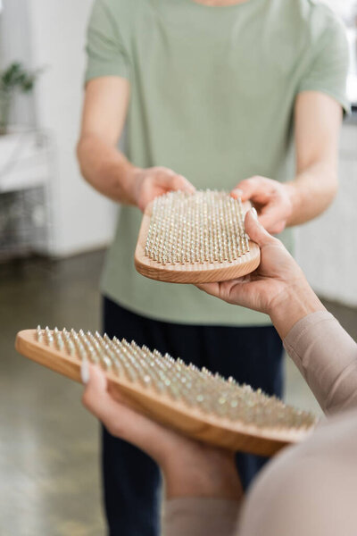 Cropped view of african american woman giving sadhu board to blurred man in yoga class 