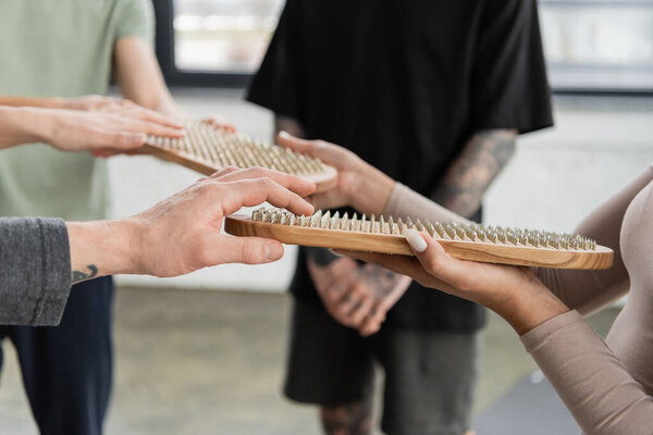 Cropped view of interracial people holding sadhu board in yoga class 