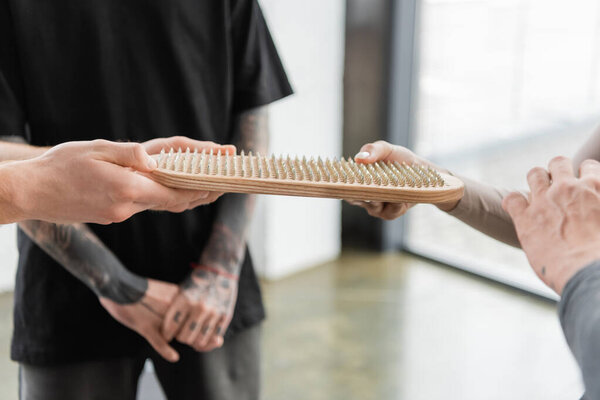 Cropped view of coach giving sadhu board to man in yoga class 