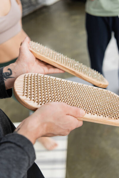 Cropped view of coach holding sadhu board near blurred people in yoga studio 