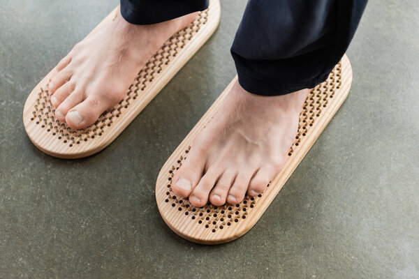 Вид сверху на человека, стоящего босыми ногами на доске садху в студии йоги