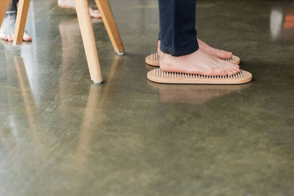 cropped view of man standing with bare feet on sadhu nail board in yoga studio