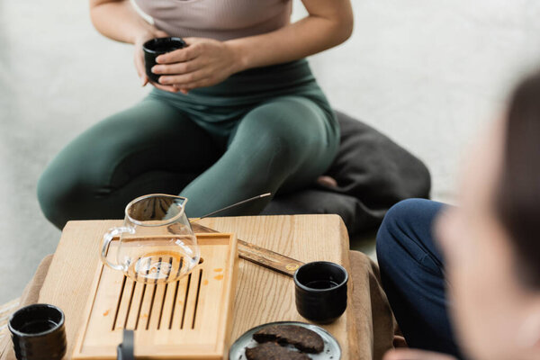 cropped view of woman holding Chinese cup near fermented puer during tea ceremony 