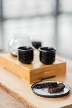 Yoga stüdyosunda Japon çay fincanlarının yanındaki tabakta sıkıştırılmış pu-erh çayı. 