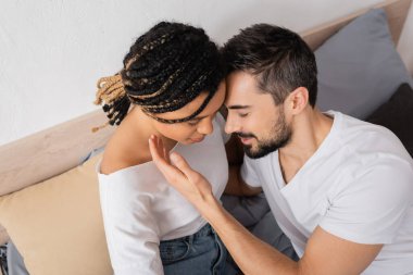 Gözü kapalı sakallı adamın yüksek açılı görüntüsü. Yatak odasında rastalı saçlı Afrikalı Amerikalı bir kadının yanında.