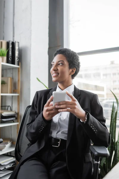 Feliz Mulher Negócios Afro Americana Terno Preto Segurando Smartphone Olhando — Fotografia de Stock