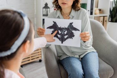 Görüşme odasındaki psikolog yakınındaki Rorschach testine işaret eden bulanık kız. 