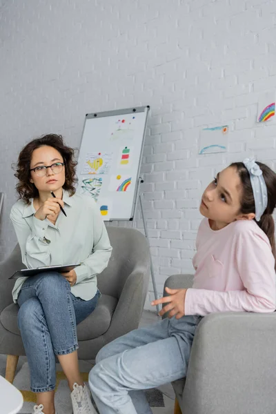 Focused Psychologist Holding Clipboard Looking Pensive Child Consulting Room — Stock Photo, Image