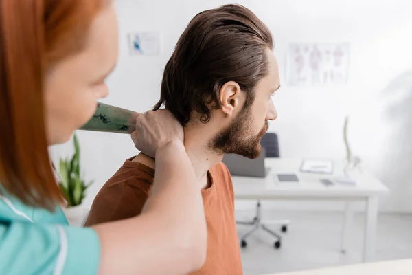 Fisioterapeuta Borrosa Examinar Cuello Del Hombre Lesionado Durante Cita Centro —  Fotos de Stock