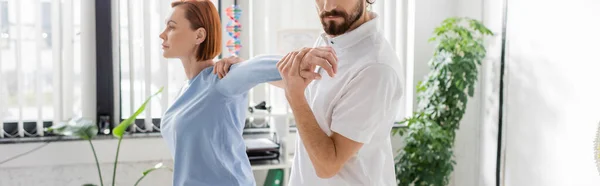 Bearded Physiotherapist Stretching Arm Redhead Woman While Doing Diagnostics Consulting — Stock Photo, Image