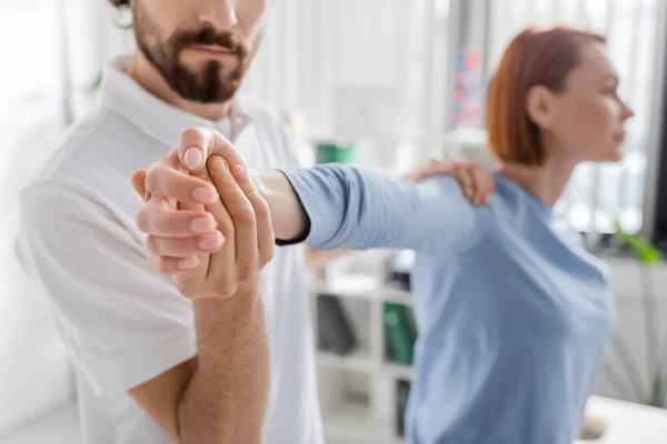 Bearded Manual Therapist Examining Injured Arm Blurred Woman Consulting Room — Stock Photo, Image