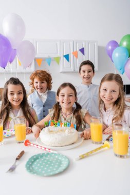 Bir grup mutlu erkek ve kız doğum günü partisini evde lezzetli pastaların yanında kutluyorlar.