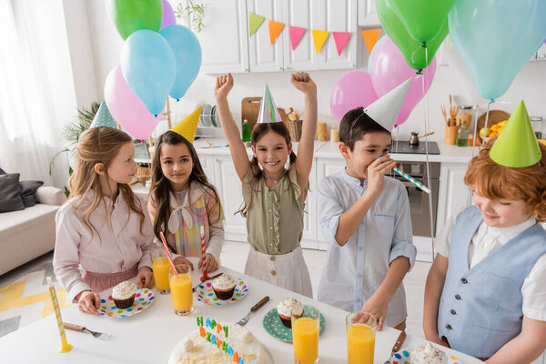группа и счастливые дети в шапочках для вечеринок веселятся во время дня рождения дома 