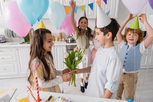 Glad Dreng Giver Tulipaner Til Munter Fødselsdag Pige Nær Venner - Stock-foto