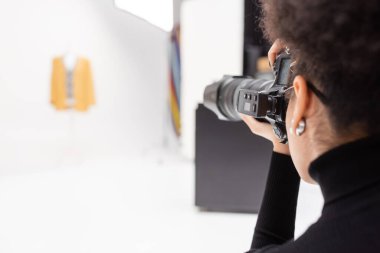 Afro-Amerikan fotoğrafçı, bulanık fotoğraf stüdyosunda profesyonel dijital kamerayla fotoğraf çekiyor.