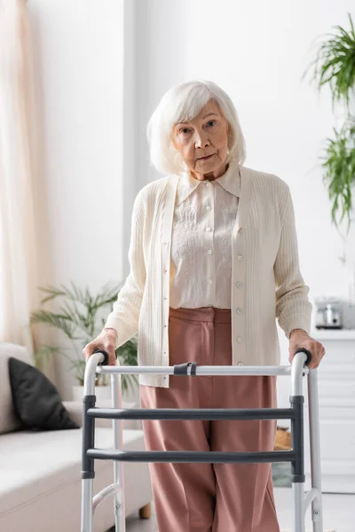 退休妇女 头发灰白 在步行者的帮助下在家里散步 — 图库照片