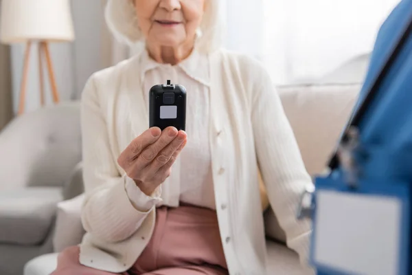 Mavi Üniformalı Hemşirenin Yanında Glukometre Tutan Mutlu Yaşlı Kadın Manzarası — Stok fotoğraf