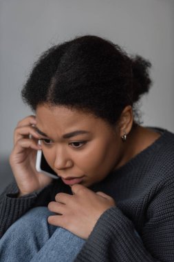Young multiracial woman with depression calling in helpline at home  clipart
