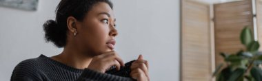 Frustrated multiracial woman with depression looking away at home, banner  clipart