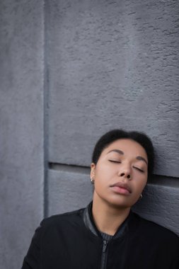 Depresyondaki genç çok ırklı kadın binanın yanında dikiliyor. 