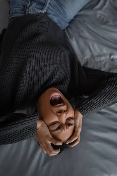 ベッドの上で横になりながらうつ病悲鳴と多人種間の女性のトップビュー — ストック写真